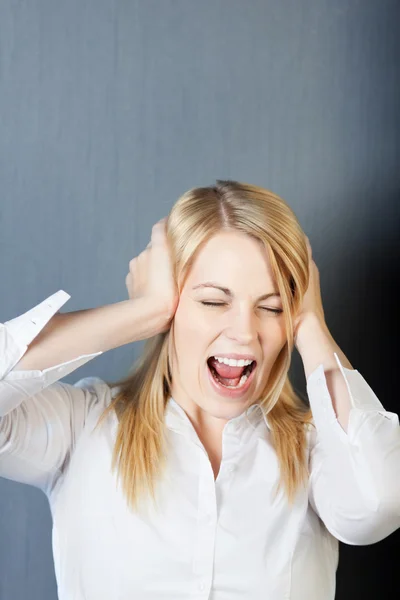 Mujer joven enojada gritando mientras cubre los oídos — Foto de Stock