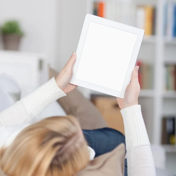 Женщина читает на электронной книге, лежа на диване — стоковое фото