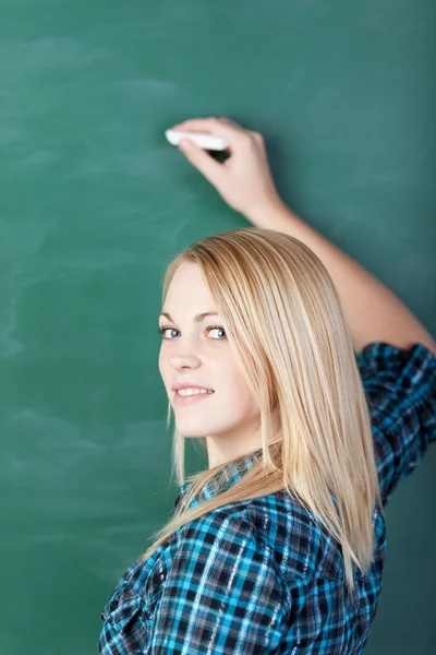 Lächelnder Student schreibt auf Tafel — Stockfoto