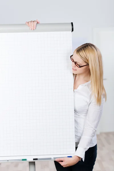 Jeune femme blonde regarde le tableau à feuilles mobiles — Photo