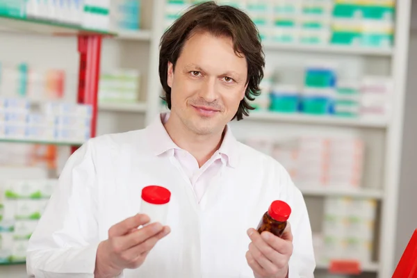 Фармацевт смотрит на бутылки с лекарствами — стоковое фото