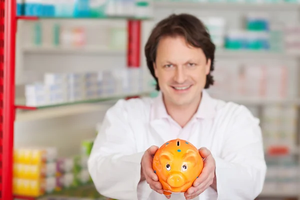 Apotheker zeigt Sparschwein — Stockfoto