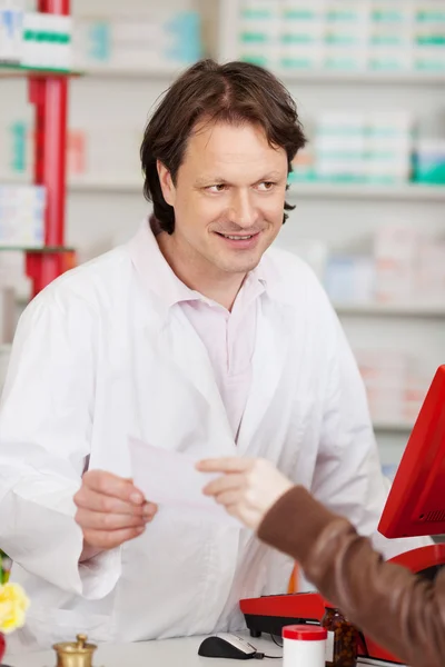 Mão passando papel de prescrição para o farmacêutico — Fotografia de Stock