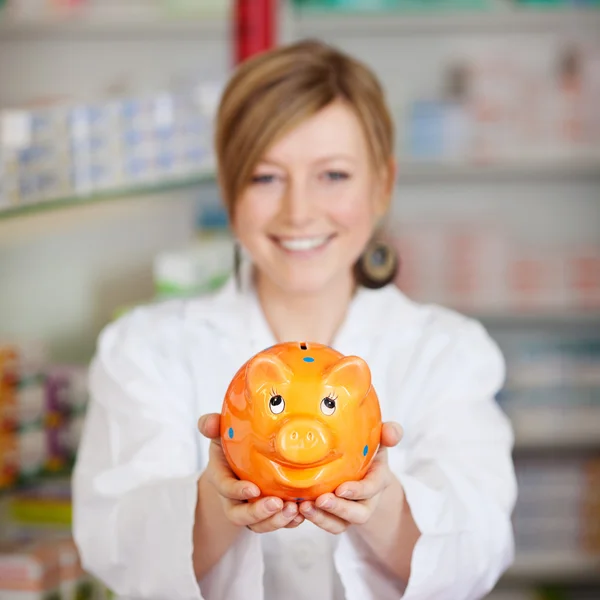 Pharmacist holding piggy bank — Stock Photo, Image
