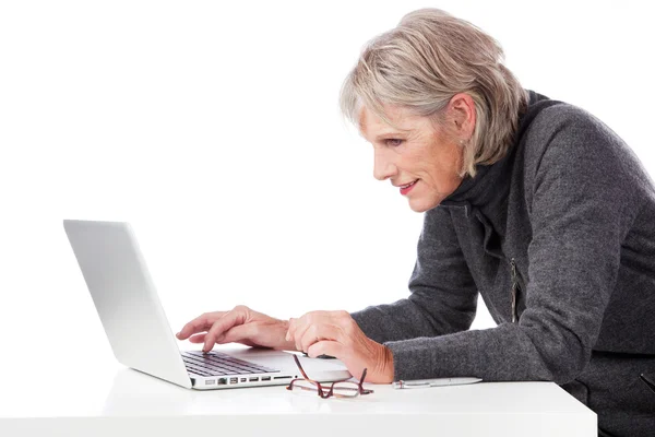 Äldre kvinna koncentrera sig när man använder sin laptop — Stockfoto