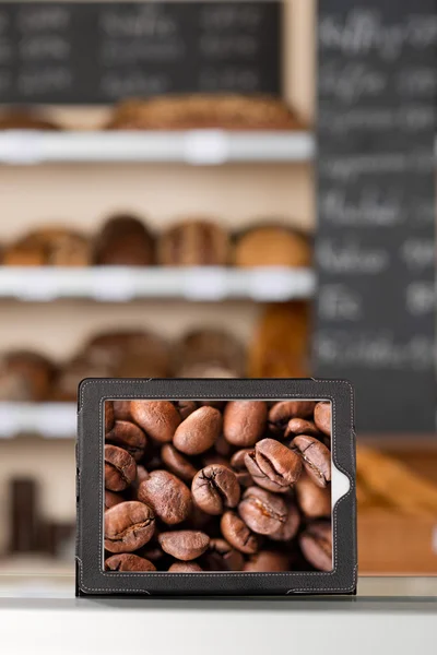 Кофе-бобы отображаются в цифровой планшет в кафе — стоковое фото