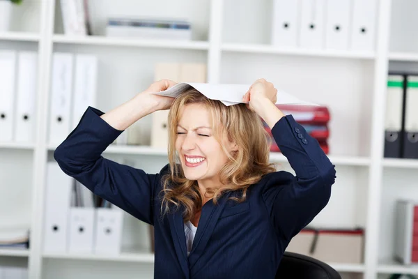Geschäftsfrau beißt Zähne zusammen, während sie Dokumente auf den Kopf legt — Stockfoto