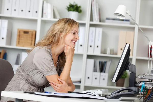 Leende affärskvinna använder dator på skrivbord i office — Stockfoto