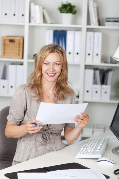 Деловая женщина держит бумагу, сидя на стуле в офисе — стоковое фото