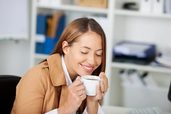 Affidabile donna d'affari che tiene una tazza di caffè alla scrivania — Foto Stock