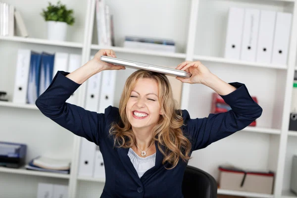 Geschäftsfrau mit Laptop auf dem Kopf beißt Zähne zusammen — Stockfoto