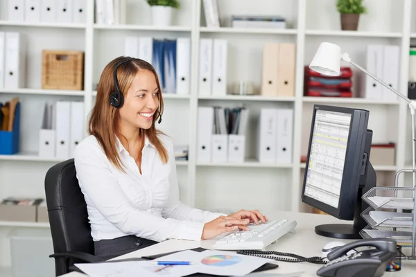 Femme d'affaires portant casque tout en utilisant l'ordinateur au bureau — Photo