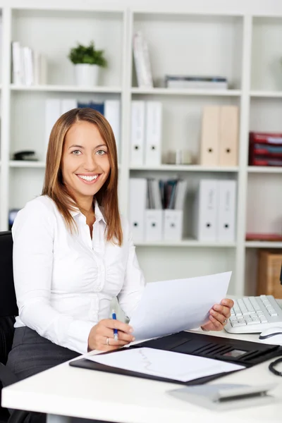 Junge Geschäftsfrau hält Dokument am Schreibtisch — Stockfoto