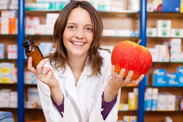 Apothekerin mit Tablettenflasche und künstlichem Apfel — Stockfoto