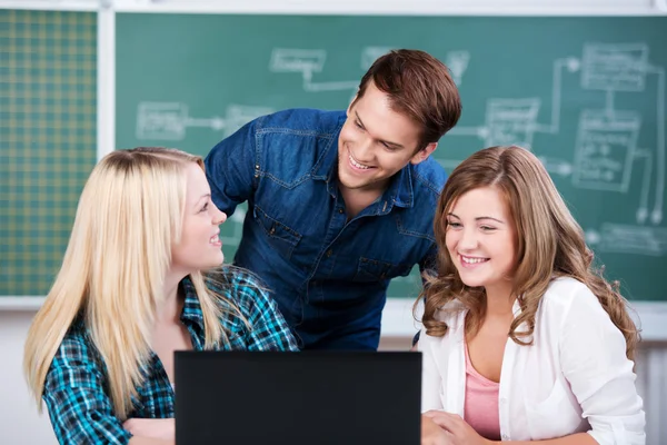 Jovens estudantes confiantes com laptop na mesa — Fotografia de Stock