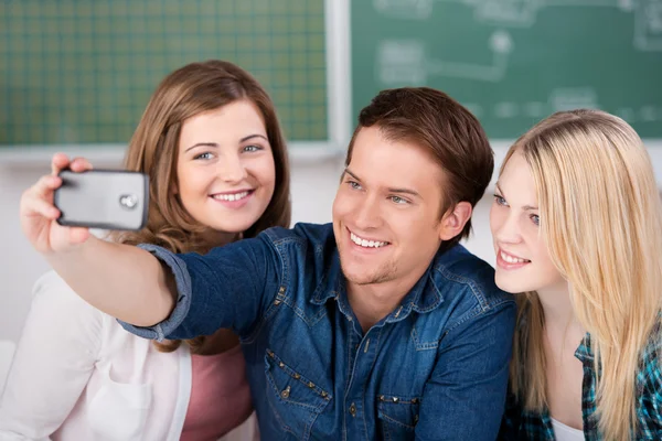 Amigos tomando autorretrato a través del teléfono móvil en el aula —  Fotos de Stock
