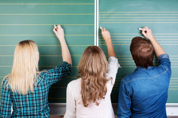 3 tiener studenten schrijven op schoolbord — Stockfoto