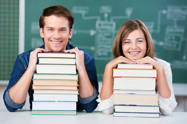 Schüler ruhen sich auf Bücherstapel am Schreibtisch aus — Stockfoto