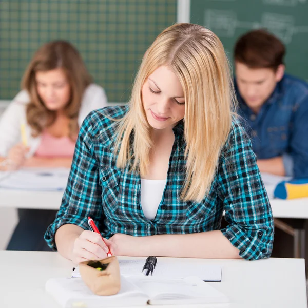 Vrouwelijke student schrijven in klas — Stockfoto