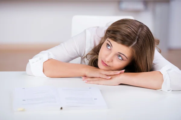 Ragazza adolescente appoggiata alla scrivania mentre guarda lontano — Foto Stock