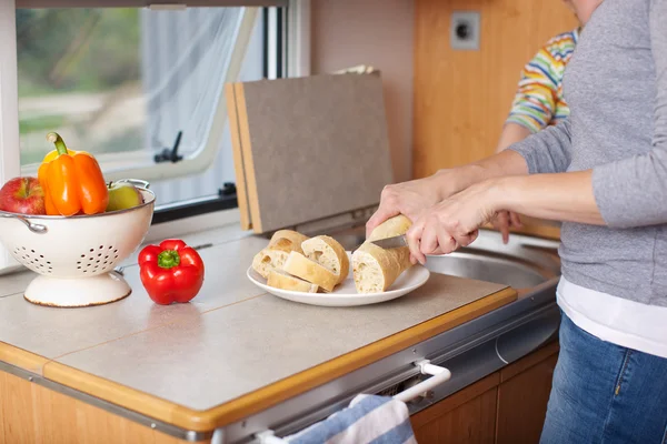 Mujer cortando pan de abalorios en el gabinete en caravana —  Fotos de Stock