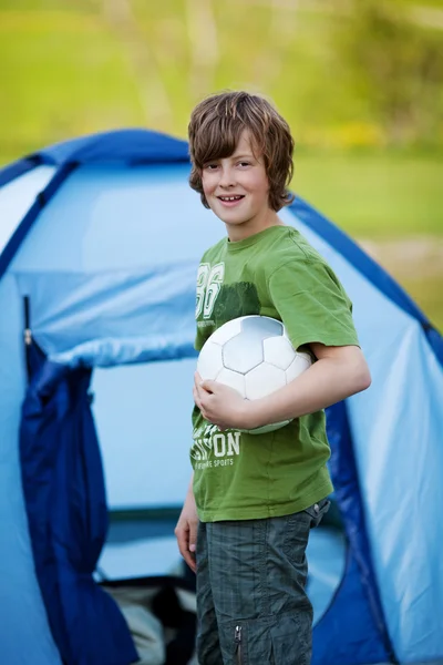 Chłopiec posiadania piłki nożnej przeciwko namiot — Zdjęcie stockowe