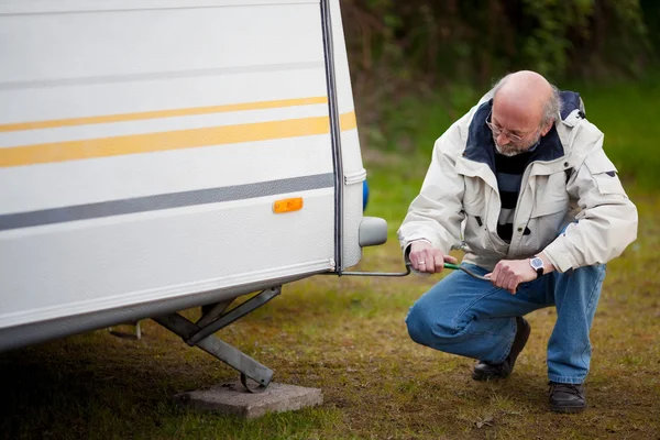 Starší muž, krčící se při opravě caravan — Stock fotografie