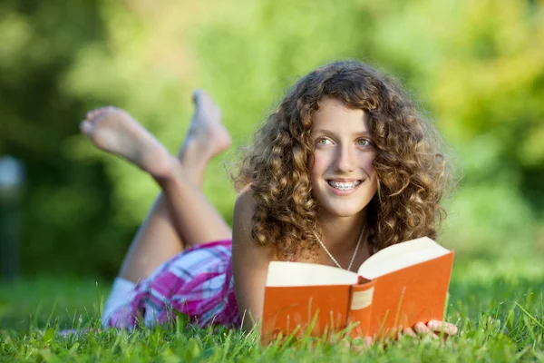 Young Girl Reading Book While Lying On Grass Royalty Free Stock Images