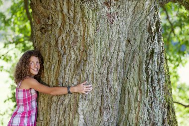 Happy Teenage Girl Embracing Tree clipart