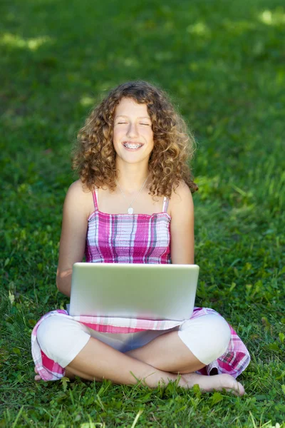 Девушка с ноутбуком сидит на траве, глаза закрыты — стоковое фото