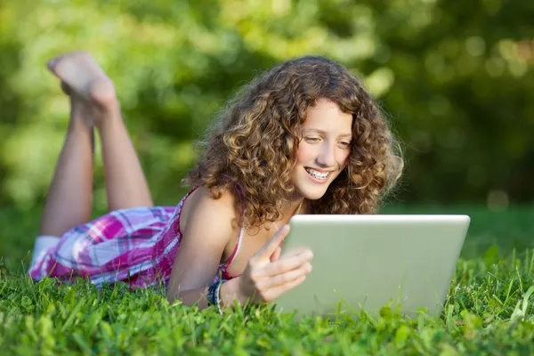 Flickan med laptop liggande på gräs — Stockfoto