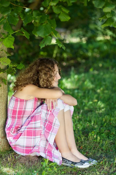 Chica mirando hacia otro lado mientras se sienta en el parque — Foto de Stock