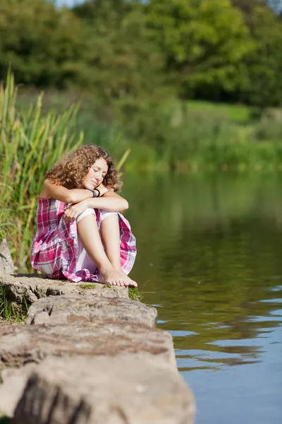 Teenager-Mädchen mit geschlossenen Augen auf einem Felsen sitzend — Stockfoto