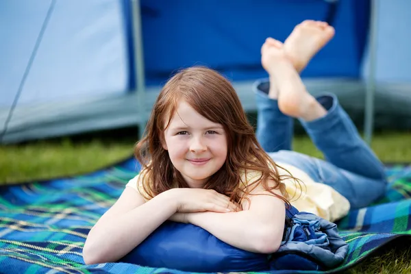 Meisje liggend op deken met tent op achtergrond — Stockfoto