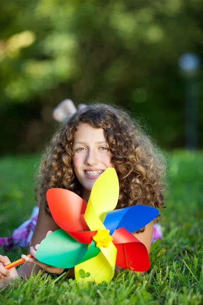 Tienermeisje met pinwheel liggen op gras — Stockfoto