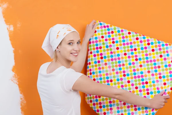 Femme tenant le papier peint contre le mur de couleur orange — Photo