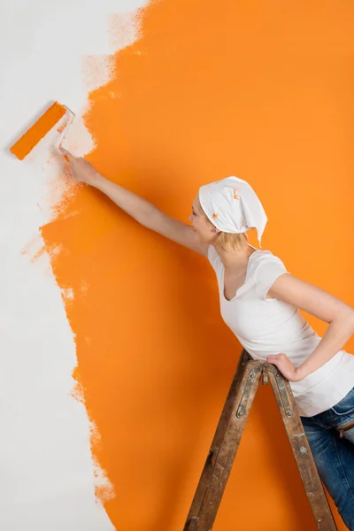 Mulher pintura parede em laranja — Fotografia de Stock