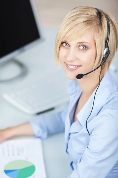 Klant dienst uitvoerend hoofdtelefoon dragen aan balie — Stockfoto