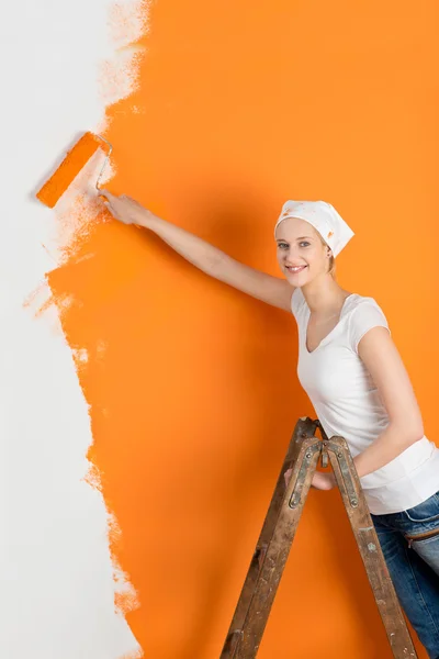 Parede jovem da pintura da mulher com rolo na casa — Fotografia de Stock