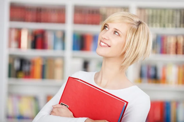 Leende student håller binder i biblioteket — Stockfoto