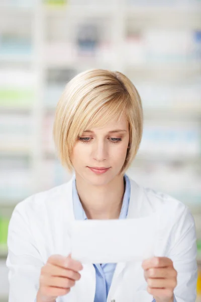 Vrouwelijke apotheker lezen op een papier — Stockfoto