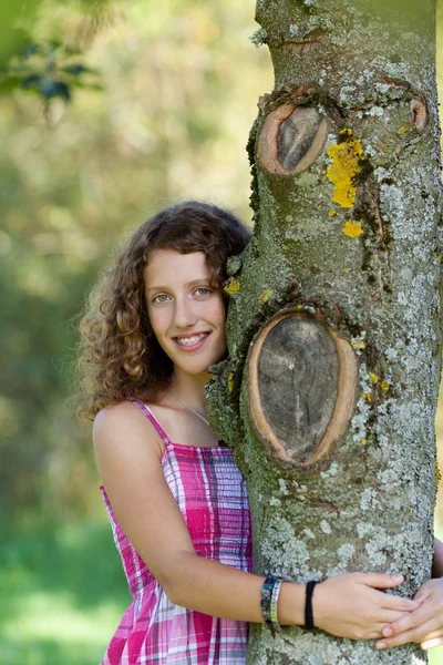 Jovem menina abraçando árvore no parque — Fotografia de Stock