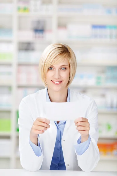 Papel de prescrição do farmacêutico fêmea que prende no balcão da farmácia — Fotografia de Stock