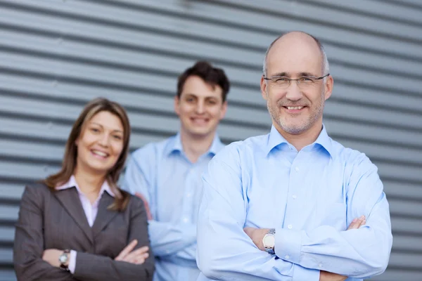 Businessteam With Arms Crossed Against Shutter — Stock Photo, Image