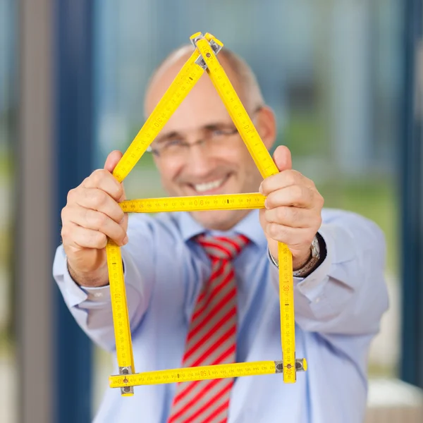 Forretningsmann som holder hus laget av Hersker. – stockfoto