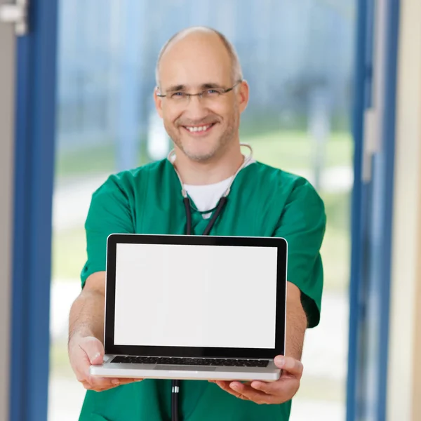 Cirurgião sorridente segurando laptop na clínica — Fotografia de Stock