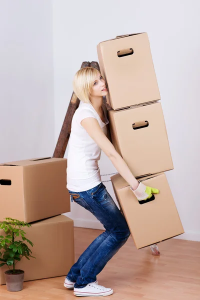 Donna che trasporta scatole di cartone pesanti in casa — Foto Stock