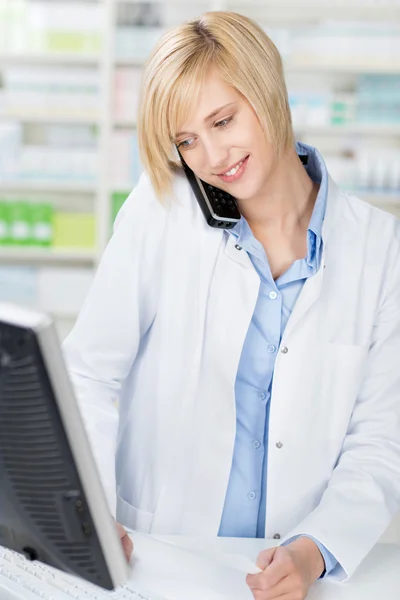 Farmacista con prescrizione utilizzando il telefono senza cordone durante lo sguardo — Foto Stock