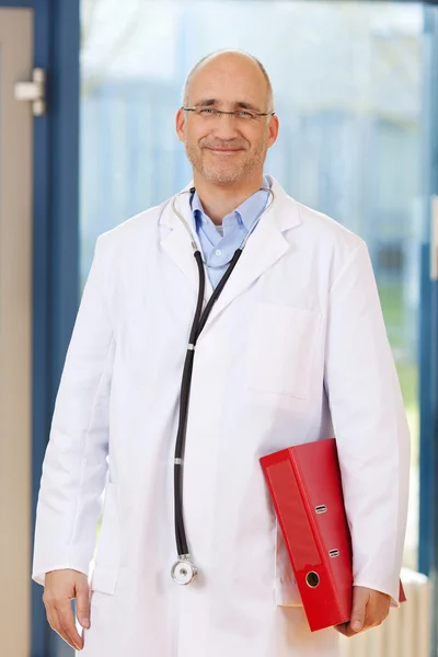 Мужской врач, держащий биндер в клинике — стоковое фото