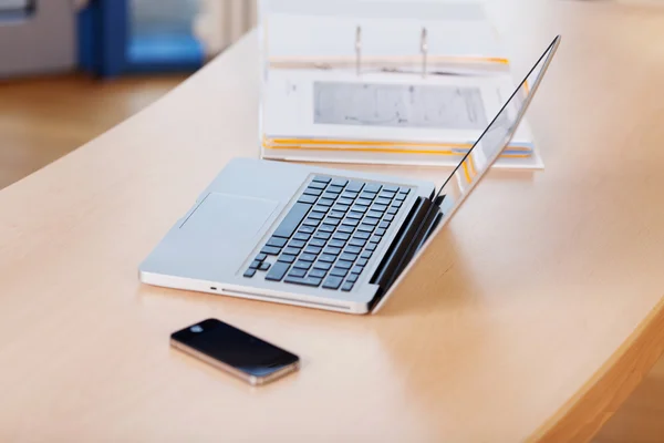 Telefon komórkowy, laptop i spoiwa na biurko — Zdjęcie stockowe